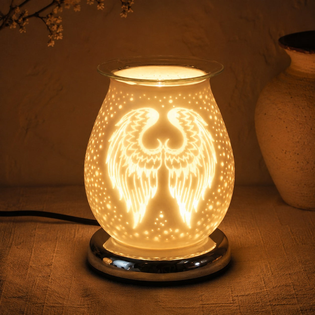 White satin angel wings burner lit at night