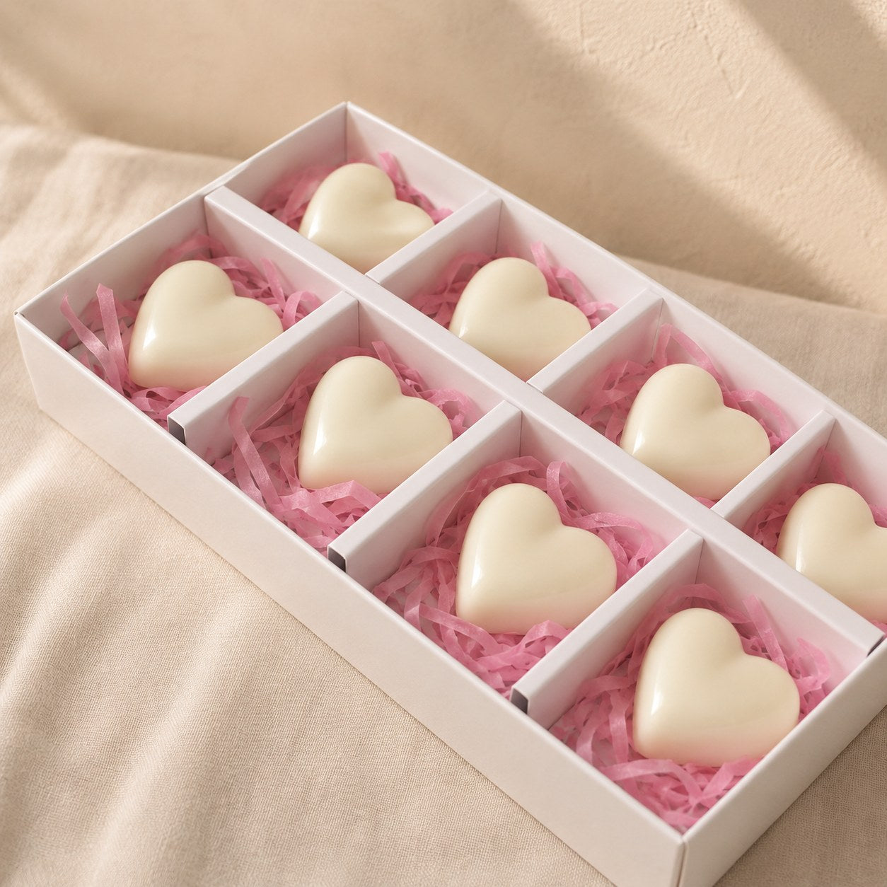 White compartment gift box of cream heart shaped wax melts on pink tissue