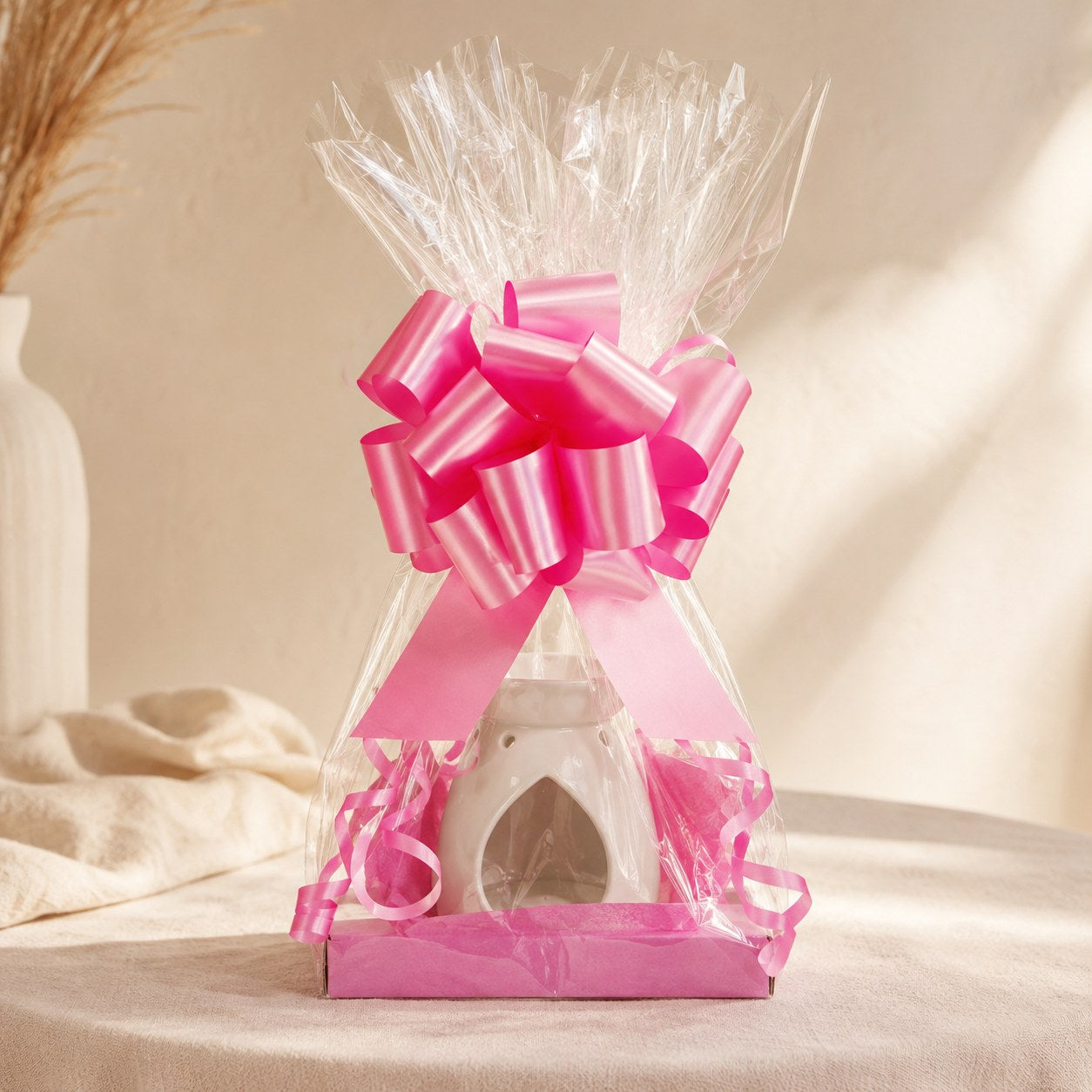 Wax burner gift wrapped in clear cellophane with a bright pink pull bow