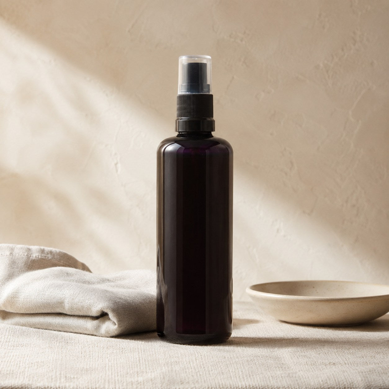 Perfume scented room spray in a dark plum bottle on linen