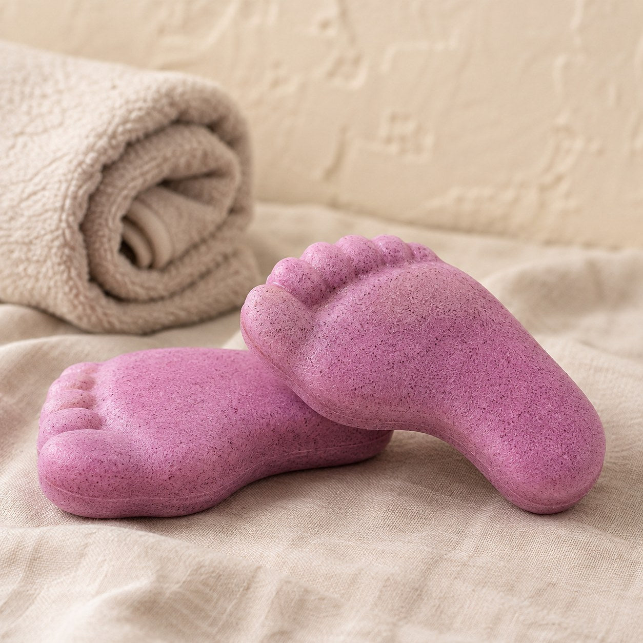 Pink foot shaped pumice exfoliating soap bars on pale linen